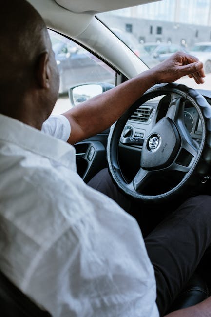pexels-photo-4606346-4606346-1 A man driving a vehicle, highlighting the steering wheel and car interior.